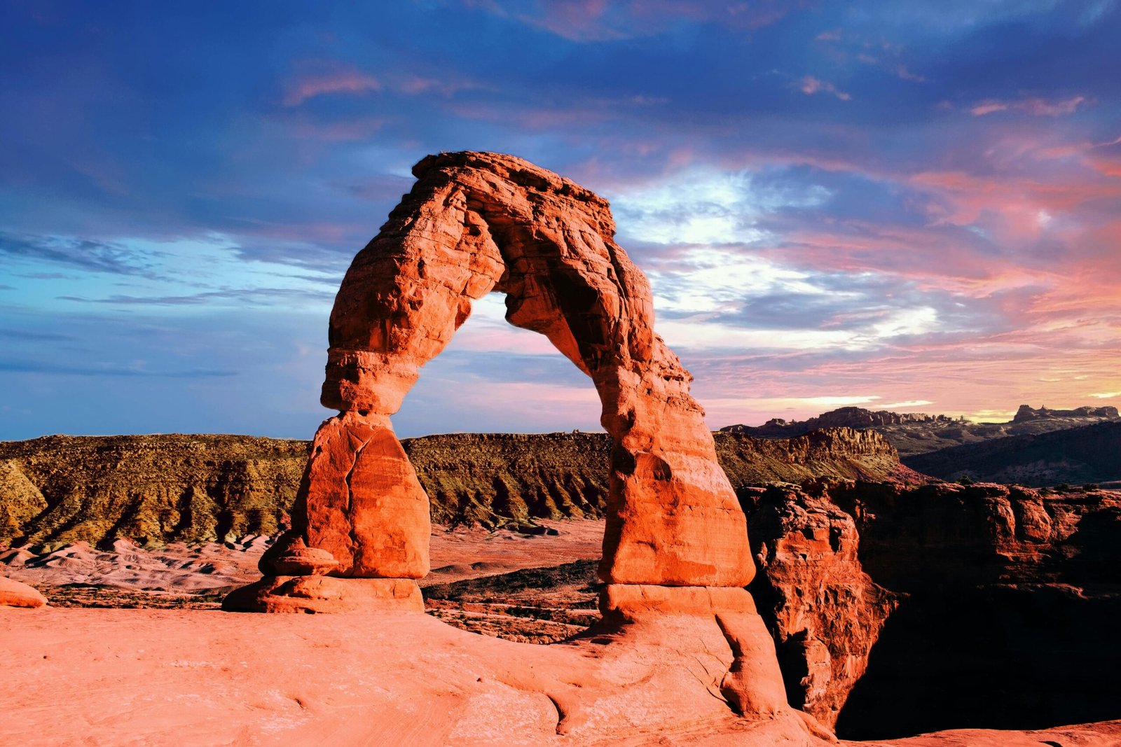 Stunning view of Delicate Arch in Arches National Park, captured at sunset with vivid colors and dramatic skies.